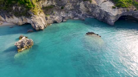 Xigia-beach-with-turquoise-waters-and-rocky-cliffs-at-sunset,-aerial-view