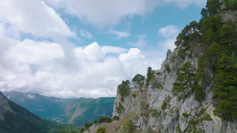 Overtaking-cliff-with-green-pines-to-cloudy-valley,-Mt-Granier,-French-Alps