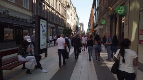 People-walk-on-Drottninggatan-in-central-Stockholm,-Sweden,-on-a-busy-summer-day