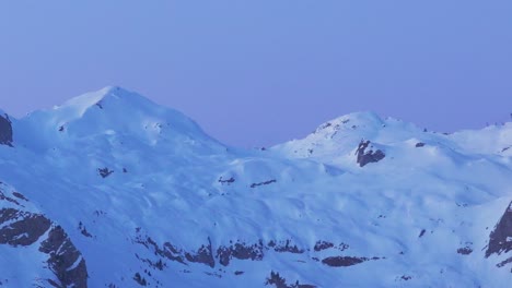 Mit-Einer-Drohne-Aufgenommenes-Filmmaterial-Zeigt-Den-ätherischen-Charme-Des-Sonnenaufgangs,-Der-Die-Silhouette-Einer-Schneebedeckten-Bergkette-Erhellt