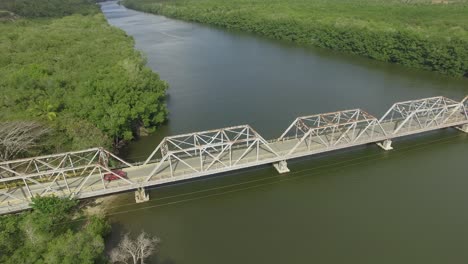 Vintage-Red-Pickup-Truck-Crosses-a-Metal-Bridge,-Aerial-Tracking,-Argentina