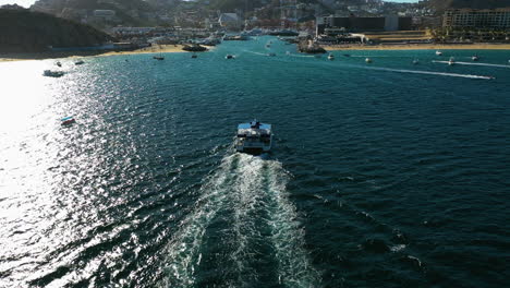 Drone-Pasando-Un-Ferry-Que-Se-Dirige-Hacia-La-Marina-De-Cabo-San-Lucas,-En-El-Soleado-México