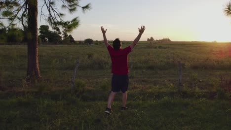 Relaxed-man-opening-his-arms-while-walking-and-contemplating-nature-at-sunset