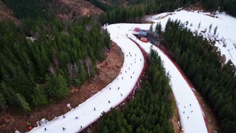 Flying-above-Dolni-Morava-skiing-track-slope-with-people-near-evergreen-forest