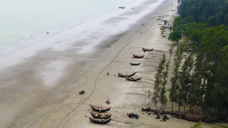 Aerial-revealing-pan-shot-of-a-shoreline-in-Bangladesh-with-traditional-boats-and-a-treeline