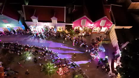 Fashion-show-models-walk-along-runway-street-at-night-in-Kura-Hulanda-village-in-Otrobanda-Willemstad-Curacao,-aerial