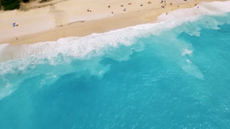 Turquoise-waves-gently-lapping-the-sandy-shores-of-Myrtos-Beach-in-Kefalonia,-Greece,-aerial-view