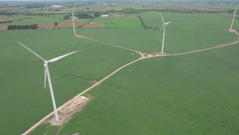 Windturbinen-Auf-Grünen-Feldern-An-Bewölkten-Tagen,-Hinweise-Auf-Erneuerbare-Energiequellen,-Luftaufnahme