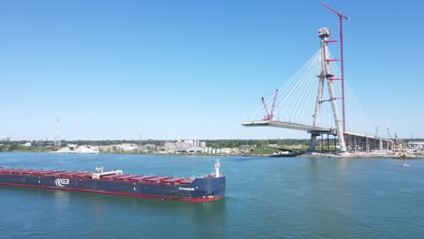 Buque-De-Carga-Navega-Bajo-El-Puente-Internacional-Gordie-Howe-Que-Se-Está-Construyendo-Sobre-El-Río-Detroit,-Vista-Aérea