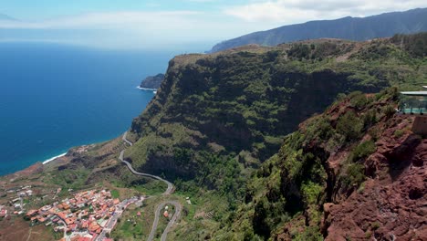 Side-Aerial-View-of-Mirador-de-Abrante,-Red-Rocky-Landscape,-Green-Coastline-in-the-Background,-La-Gomera-Island