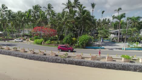 Seguimiento-Aéreo-De-Un-Coche-Rojo-En-La-Carretera-Costera-De-La-Ciudad-De-La-Playa,-Las-Terrenas.