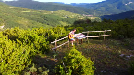 Hombre-Tocando-La-Guitarra-Clásica-En-La-Naturaleza-Entre-Montañas-Y-Pueblos