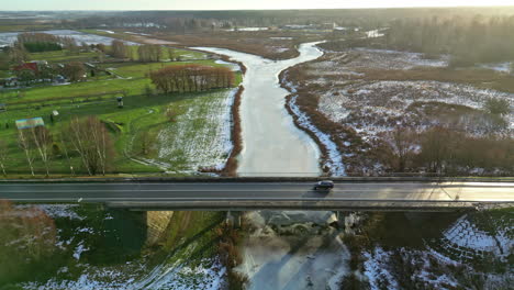 Car-Driving-Through-The-Bridge-Over-Frozen-River-In-Winter