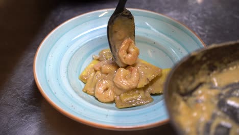 Adding-ravioli-with-shrimp-in-sour-cream-onto-a-plate