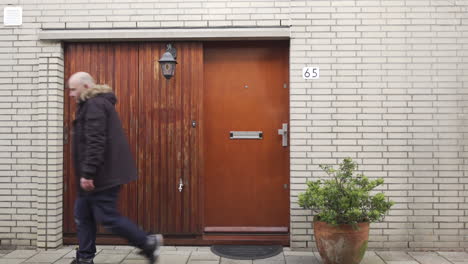 Bald-man-wearing-warm-jacket-closing-door-at-home