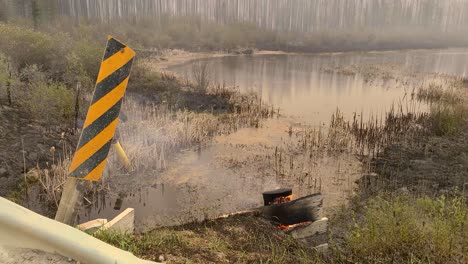 Diagonal-Yellow-And-Black-Stripes-Hazard-Warning-Sign-Next-To-A-Wood-Burning-During-Wildfire