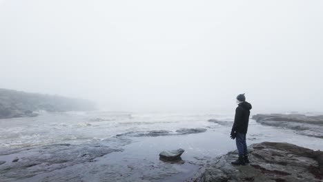 Un-Joven-Parado-Sobre-Las-Rocas-En-Un-Paisaje-Costero.