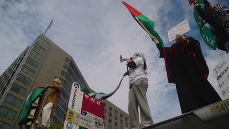 Mujeres-árabes-Sosteniendo-Carteles,-Gritando-Y-Ondeando-Banderas-En-Lo-Alto-De-Una-Parada-De-Autobús-En-Una-Protesta-A-Favor-De-Palestina.