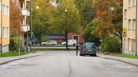 Street-traffic-and-trees-in-Stockholm-in-autumn,-man-gets-into-car