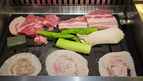 Koreanisches-BBQ---Scheiben-Von-Rohem-Schweinebauch-Mit-Sichtbaren-Fettschichten-Und-Fleisch-Auf-Dem-Grill-Gebraten-Mit-Pilzen-Und-Frühlingszwiebeln-Im-Restaurant---Nahaufnahme