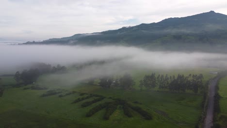 Slow-moving-drone-clip-over-a-green-field-with-the-volcano-Volcan-Pasochoa-at-the-background-in-Neblina,-Machachi-in-Equador