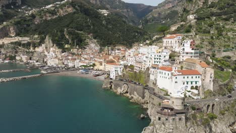 Costa-De-Amalfi-Con-Aguas-Cristalinas-Y-Edificios-Junto-Al-Acantilado-A-La-Luz-Del-Día,-Vista-Aérea