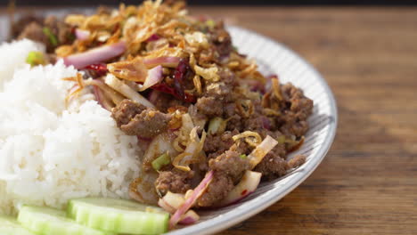 Laos-National-Dish-Beeef-Larb,-plated-beef-onion-rice-dish-with-cucmbers,-slider-close-up-4K