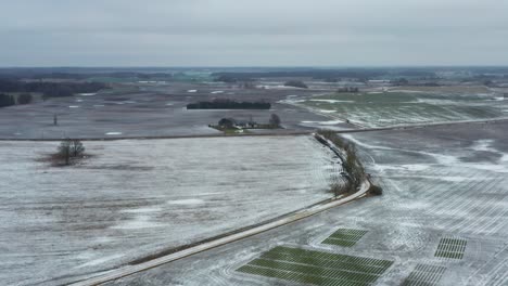 Luftaufnahme-Von-Gefrorenem-Ackerland-Und-Der-Baumgrenze-Der-Schotterstraßen-Im-Winter