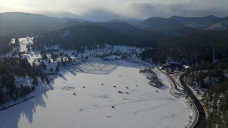 Sunset-Ice-skating-skate-hockey-rink-lake-pond-hockey-winter-Etown-Evergreen-Lake-house-fishing-tents-Denver-golf-course-Colorado-aerial-drone-golden-hour-winter-snow-traffic-forward-pan-up-reveal