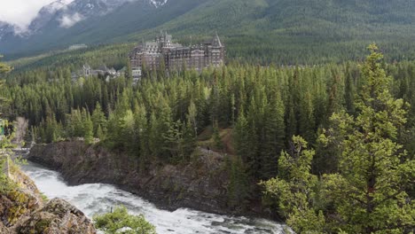 Flowing-River-With-Hotel-And-Mountains-In-Background-May-10,-2023