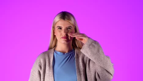 Serious-woman-rubs-her-nose-with-her-hand-suffering-from-cold,-studio-shot,-portrait-with-infinite-violet-background