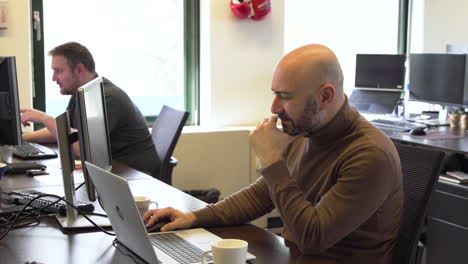 Male-office-worker-focussed-on-his-laptop-during-working-hours,-static-shot