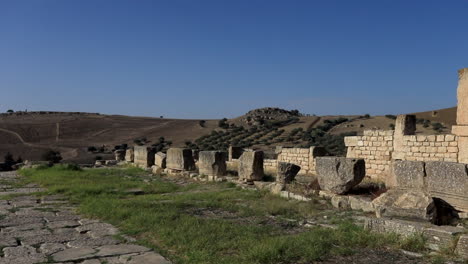 Ancient-Roman-ruins-in-Dougga-against-a-clear-blue-sky,-sunny-day