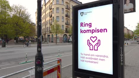 Corona-virus-info-on-digital-street-sign-in-Stockholm,-traffic-in-background