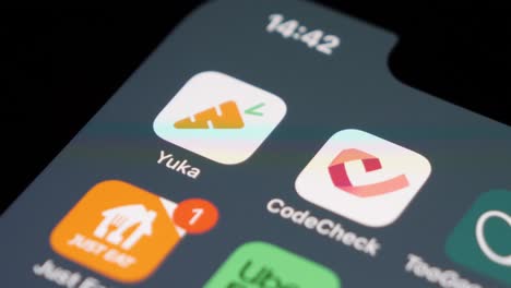 Close-up-of-a-user-swiping-on-a-smartphone,-Yuka-app-in-focus,-blurred-icons-in-background