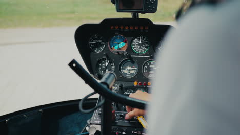 Robinson-R44-instrument-panel-and-control-joystick-mid-flight-over-a-field-in-Estonia