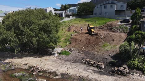 Excavadora-Amarilla-Limpiando-Un-Terreno-Empinado-Empujando-El-Suelo-Colina-Abajo