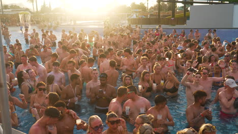 Crowd-of-young-adults-swimming-and-dancing-to-music-in-sunlit-Mallorca-pool-party-at-sunset