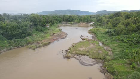 Aerial-view,-murky-river-water-in-a-forest-area-in-the-tropical-country,-Indonesia