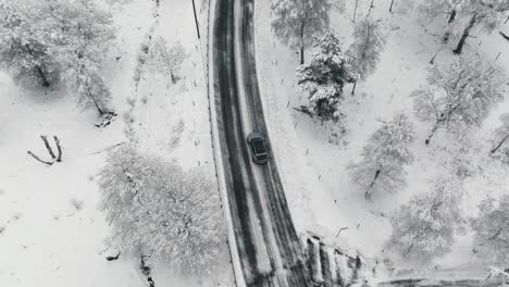 Drone-footage-of-car-driving-in-the-winter-forest-road