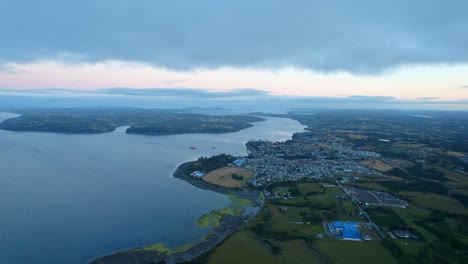 Isla-De-Chiloé-Al-Atardecer,-Mostrando-El-Vasto-Océano,-Pueblos-Pintorescos-Y-Un-Paisaje-Sereno,-Chonchi-Al-Fondo,-Vista-Aérea