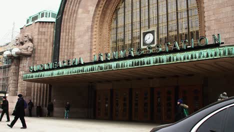 Fachada-De-La-Estación-Central-De-Helsinki-Con-Reloj,-Gente-Pululando-A-La-Luz-Del-Día