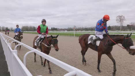 Horses-and-jockeys-galloping-back-after-a-racehorse-competition-on-a-sand-track