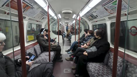 Viajeros-Sentados-A-Bordo-Del-Metro-De-La-Línea-Bakerloo-En-El-Metro-De-Londres,-Ilustrando-El-Concepto-De-Desplazamiento-Urbano-Y-Eficiencia-Del-Transporte-Público.