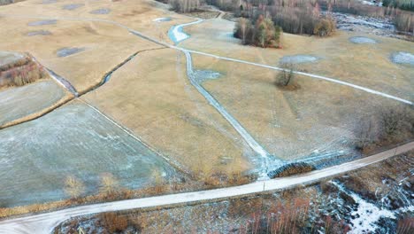 Luftaufnahme-Einer-Gefrorenen-Ackerwiese-Und-Einer-Schotterstraße-Auf-Dem-Land