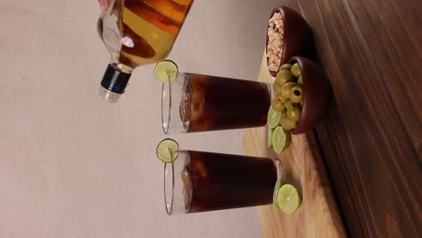 Chilenischer-Piscola-Drink,-Typischer-Sommercocktail-Aus-Chile,-Glas-Mit-Eis,-Holzbrett-Und-Zitronen-Auf-Hellem-Hintergrund-Mit-Selektivem-Fokus