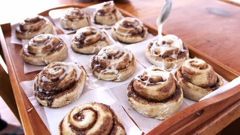 Freshly-baked-cinnamon-buns-being-glazed-with-sugar