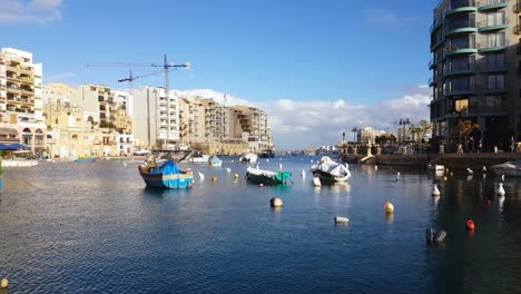 Promenade-Von-Sliema,-Traditionelle-Maltesische-Boote,-Luzzu-Schwimmend-Im-Ruhigen-Meerwasser