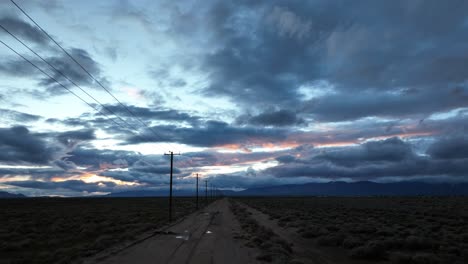 Wüstenstraße,-Die-Sich-Bis-Zum-Horizont-Erstreckt,-Unter-Einem-Dramatischen-Dämmerungshimmel-In-Der-Mojave