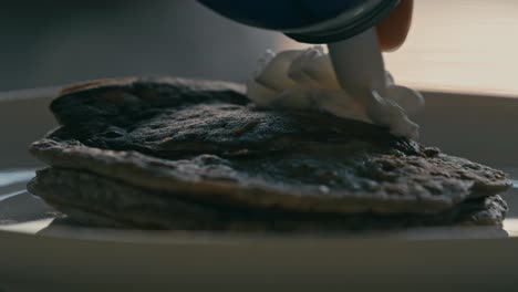 Extreme-closeup-of-cream-swirling-on-blueberry-pancakes-against-the-backdrop-of-gentle-illumination